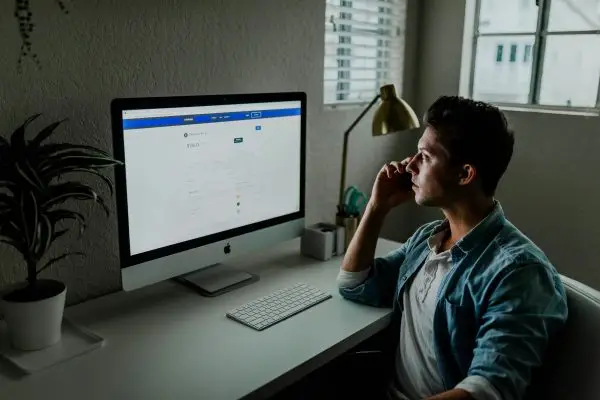 man-in-front-of-a-desktop-talking-on-a-phone
